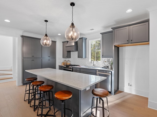 kitchen with light stone counters, stainless steel appliances, a center island, light hardwood / wood-style floors, and hanging light fixtures