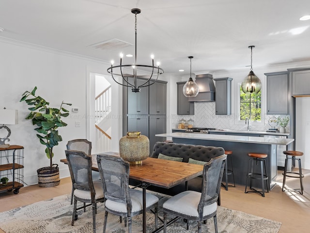 dining space with a chandelier, light hardwood / wood-style flooring, crown molding, and sink