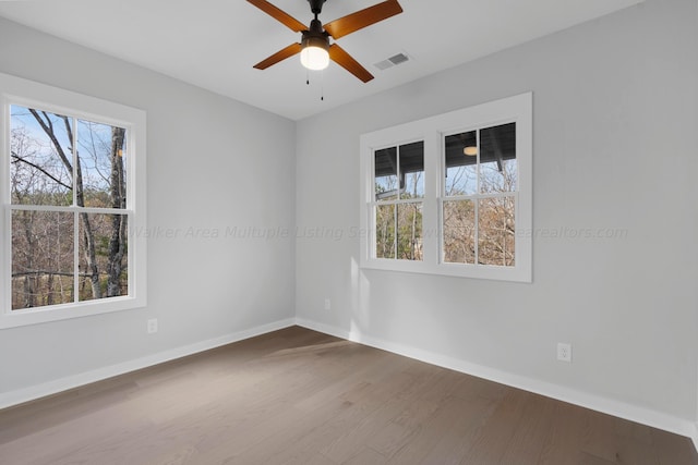 unfurnished room featuring ceiling fan, wood-type flooring, and a wealth of natural light