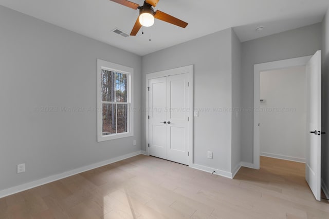 unfurnished bedroom with ceiling fan, light wood-type flooring, and a closet