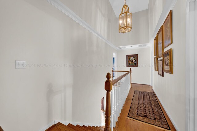 hall with a towering ceiling, hardwood / wood-style flooring, and a notable chandelier