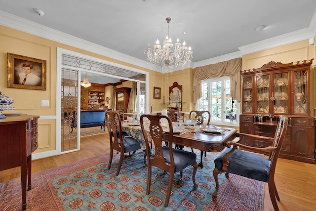 dining room with a notable chandelier, light wood-type flooring, and crown molding