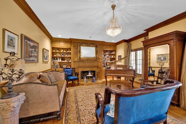 living room featuring built in shelves, crown molding, an inviting chandelier, and light wood-type flooring