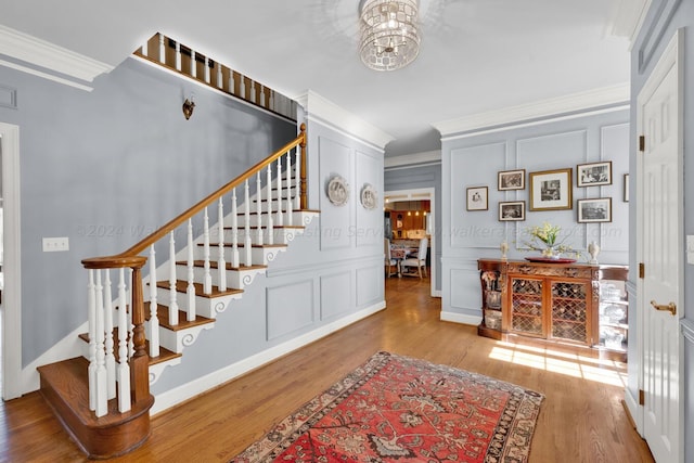 staircase featuring hardwood / wood-style flooring, crown molding, and a notable chandelier