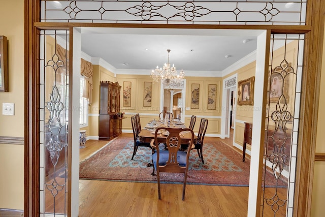 dining room with ornamental molding, light hardwood / wood-style floors, and a notable chandelier