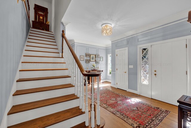 foyer entrance featuring a chandelier, light hardwood / wood-style floors, and ornamental molding