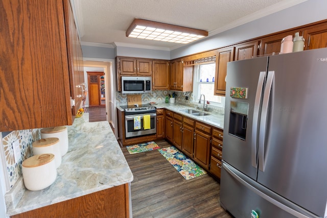 kitchen with crown molding, backsplash, appliances with stainless steel finishes, brown cabinetry, and a sink