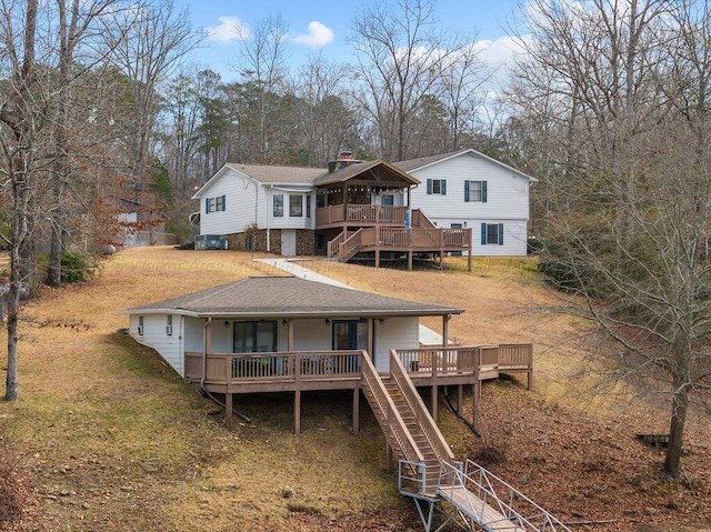 back of property with a wooden deck, stairs, a yard, and roof with shingles