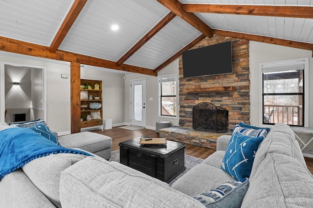 living room with lofted ceiling with beams, wood-type flooring, a stone fireplace, and wood ceiling