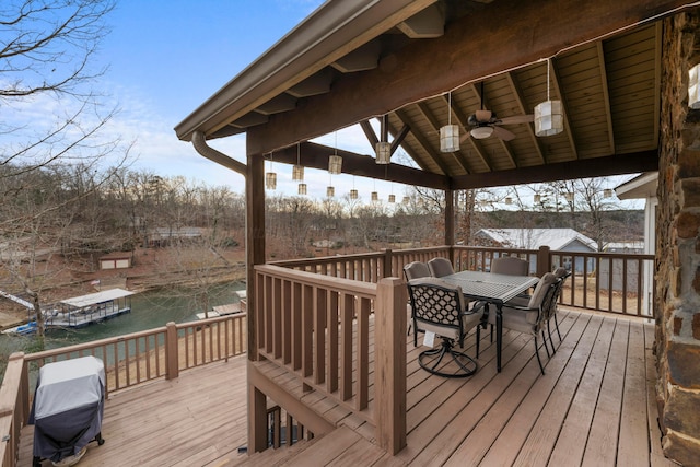 wooden deck with a water view, outdoor dining space, a ceiling fan, a gazebo, and a grill