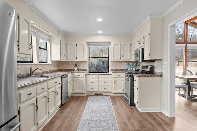 kitchen with ornamental molding, a sink, backsplash, stainless steel appliances, and light wood-style floors