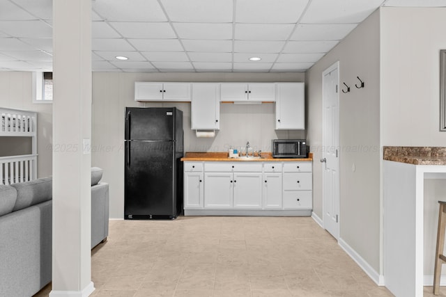 kitchen with wood counters, white cabinetry, sink, black appliances, and a drop ceiling