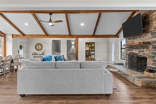 living room featuring wood-type flooring, vaulted ceiling with beams, ceiling fan, and a fireplace