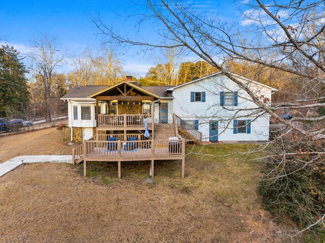 rear view of property with a yard, a deck, stairs, and a shingled roof