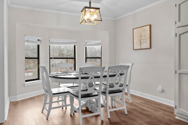 dining area featuring a chandelier, crown molding, baseboards, and wood finished floors