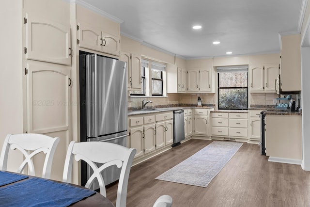 kitchen with sink, dark hardwood / wood-style flooring, decorative backsplash, stainless steel appliances, and crown molding