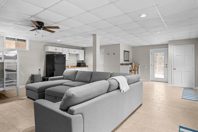 living room with ceiling fan, light tile patterned floors, and a drop ceiling