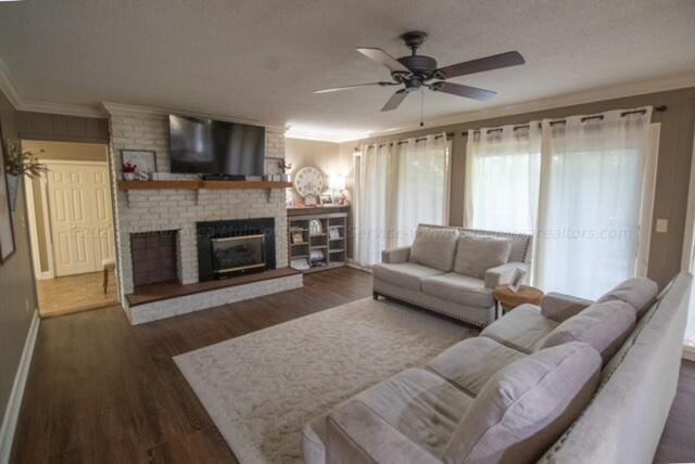 living room with a brick fireplace, ceiling fan, dark hardwood / wood-style floors, and ornamental molding