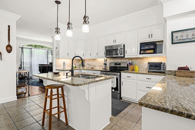 kitchen featuring an island with sink, sink, white cabinets, and stainless steel appliances