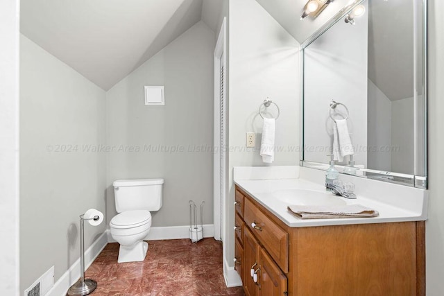 bathroom featuring vanity, toilet, and vaulted ceiling