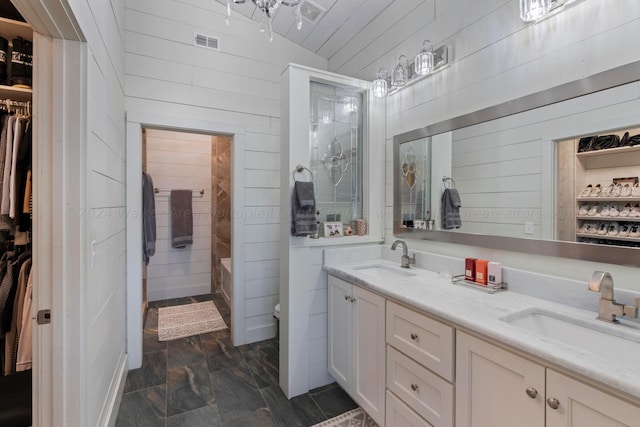 full bath featuring visible vents, a sink, wooden walls, and a spacious closet