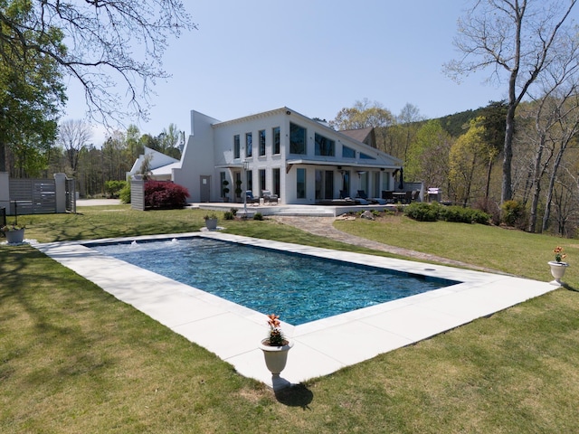 back of house with a patio area, stucco siding, an outdoor pool, and a yard