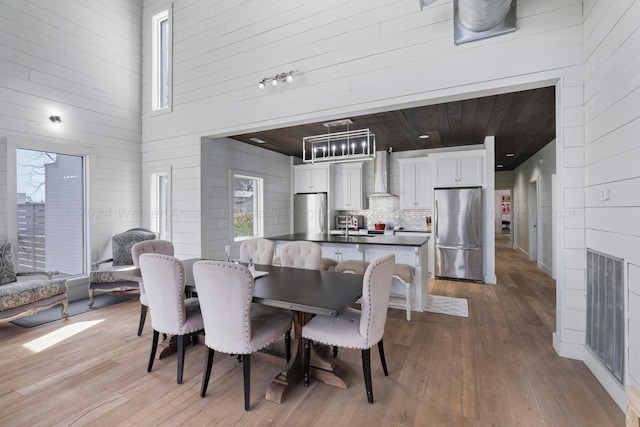 dining area with visible vents, a high ceiling, and light wood-style flooring