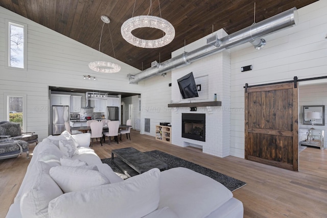 living room featuring high vaulted ceiling, a barn door, wooden walls, wood finished floors, and wood ceiling