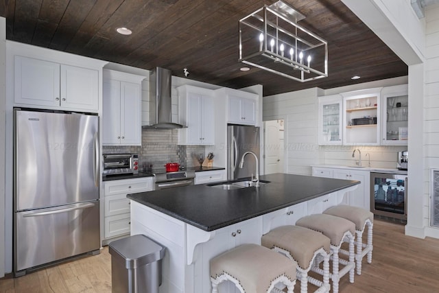 kitchen featuring wine cooler, a sink, wood ceiling, appliances with stainless steel finishes, and wall chimney range hood