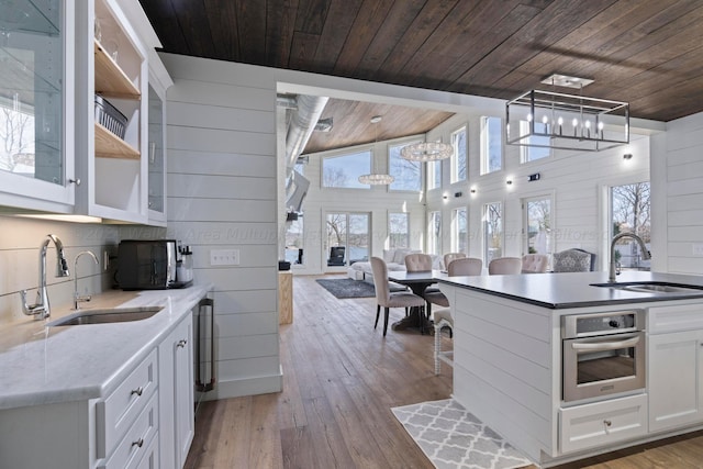 kitchen with wood ceiling, oven, a sink, and a notable chandelier