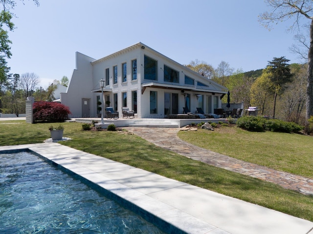 rear view of property featuring a lawn and stucco siding