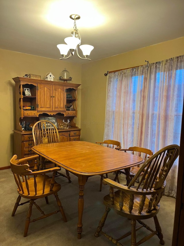 dining space featuring light carpet and a chandelier