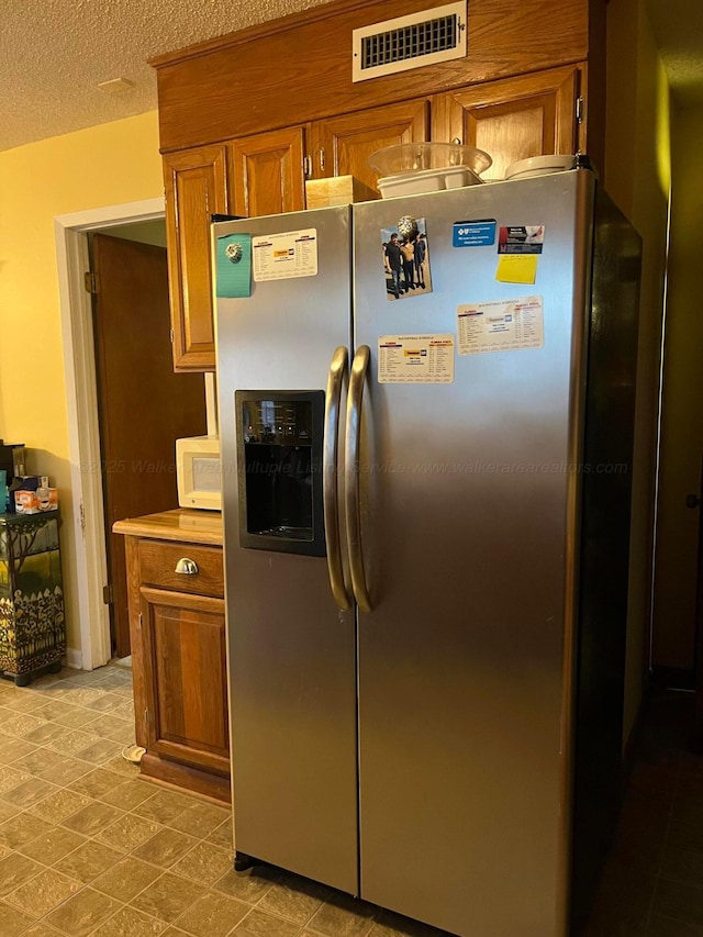 kitchen with a textured ceiling and stainless steel fridge with ice dispenser