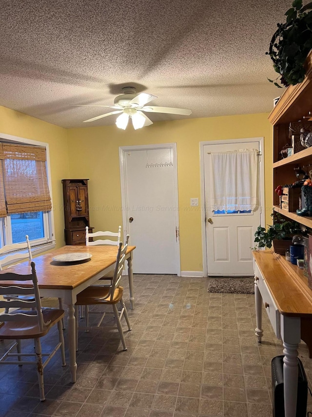 dining area featuring ceiling fan and a textured ceiling