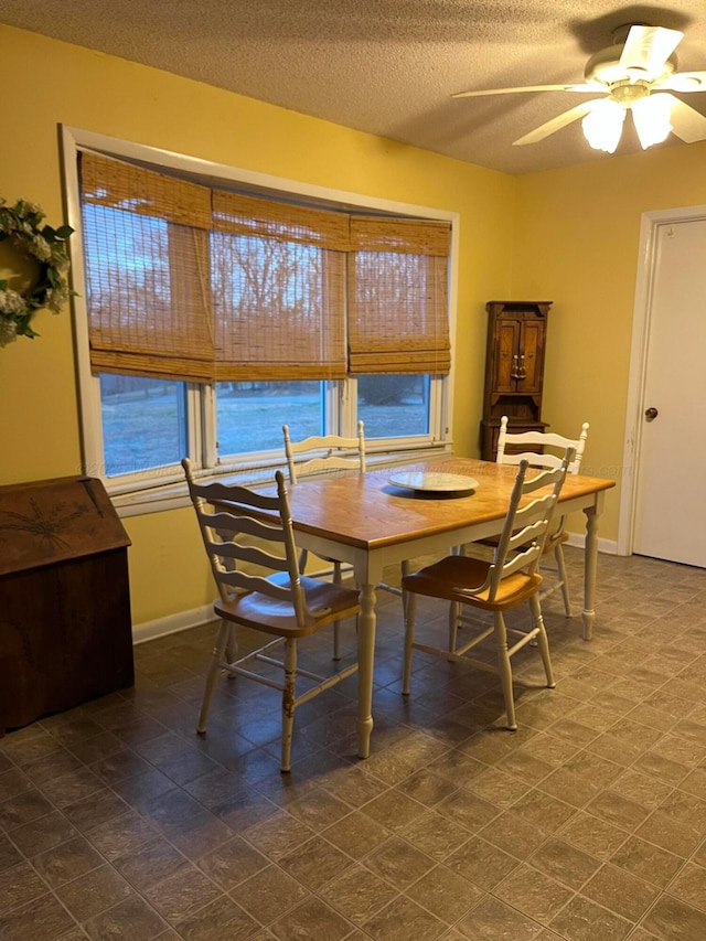 dining room with a textured ceiling, a water view, and ceiling fan