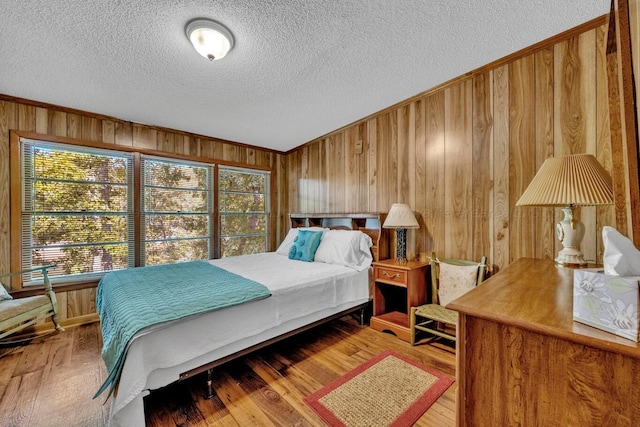 bedroom with wood-type flooring, a textured ceiling, and wood walls