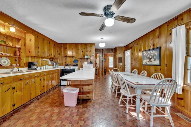 kitchen featuring a textured ceiling, wood walls, sink, and white appliances