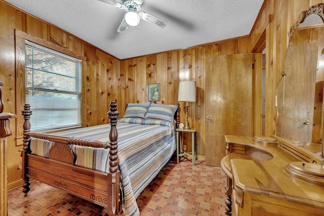 bedroom with ceiling fan, crown molding, a textured ceiling, and wooden walls