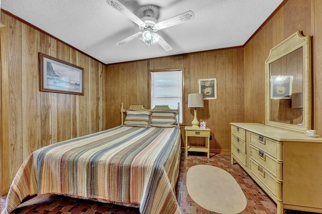 bedroom with ceiling fan, wood walls, ornamental molding, and a textured ceiling