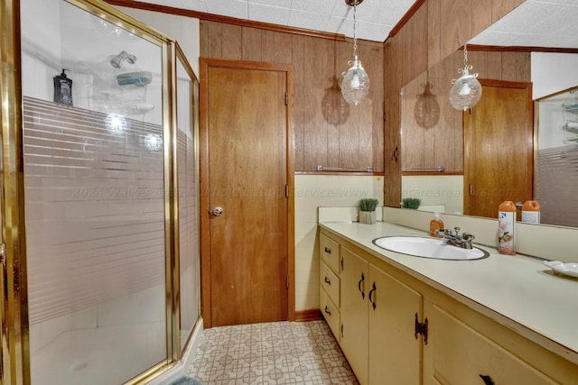 bathroom with wooden walls, crown molding, vanity, and a shower with shower door