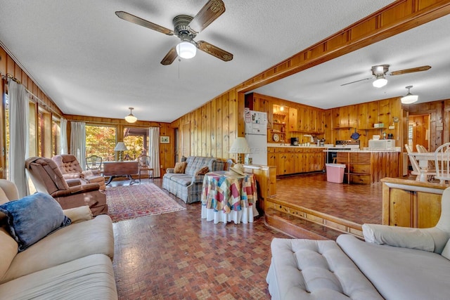 living room with a textured ceiling, ceiling fan, and wooden walls