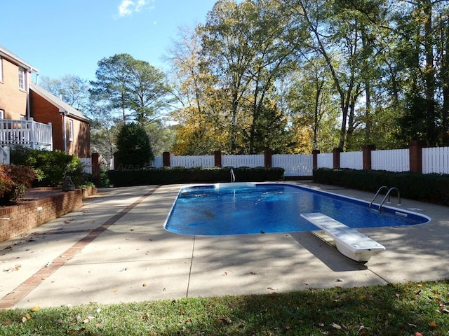 view of pool with a diving board and a patio area