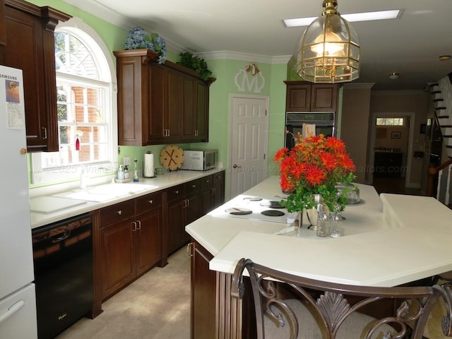 kitchen featuring decorative light fixtures, crown molding, sink, and black appliances