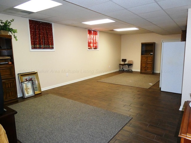 basement with dark hardwood / wood-style flooring, a drop ceiling, and white fridge