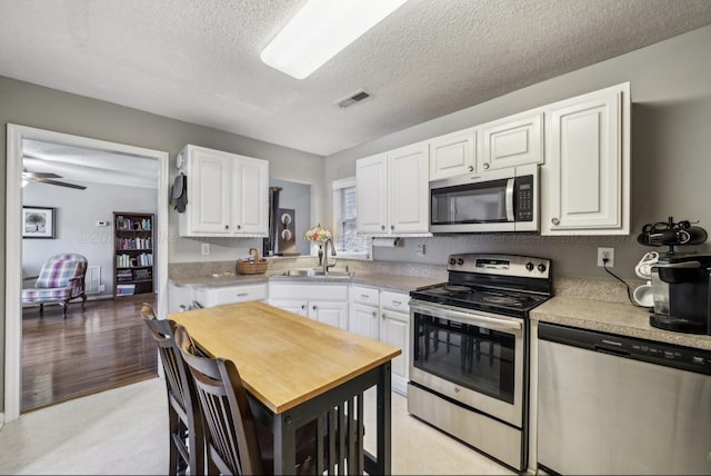 kitchen featuring white cabinetry, sink, stainless steel appliances, and a textured ceiling