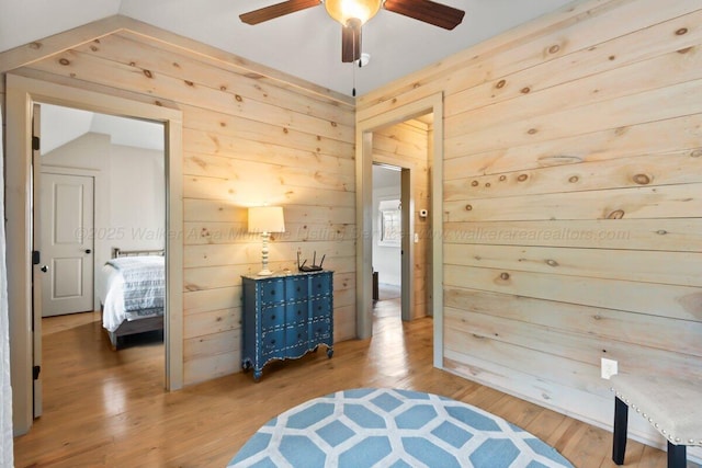 living area with hardwood / wood-style flooring, ceiling fan, and wood walls