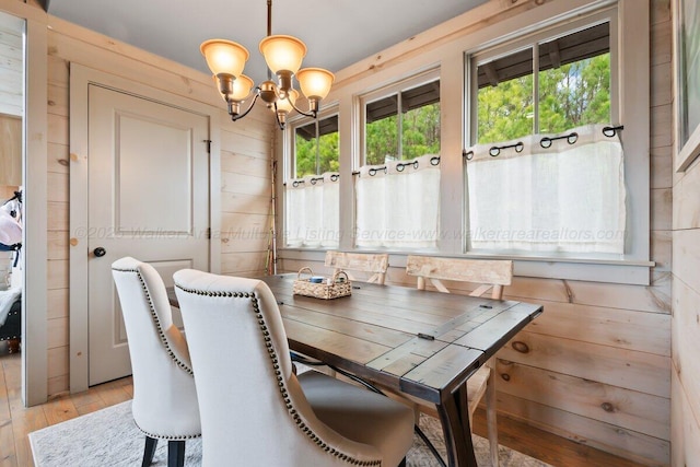 dining space with an inviting chandelier, light hardwood / wood-style floors, and wood walls