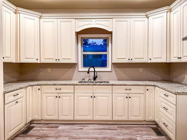 kitchen featuring light wood-type flooring, light stone counters, and sink