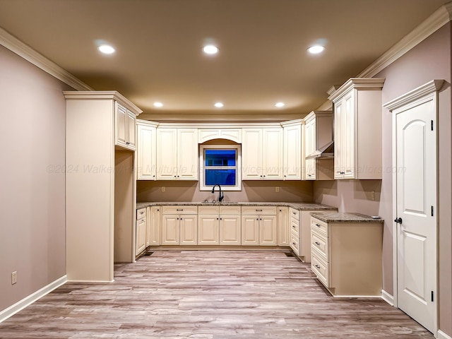 kitchen featuring light stone countertops, light hardwood / wood-style floors, ornamental molding, and sink