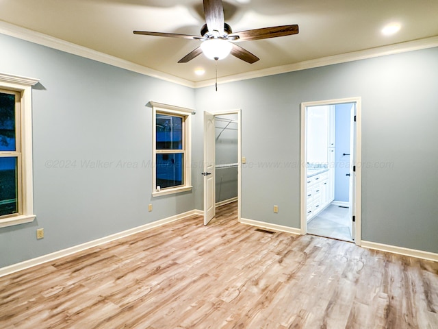 unfurnished bedroom with ceiling fan, crown molding, a spacious closet, connected bathroom, and a closet